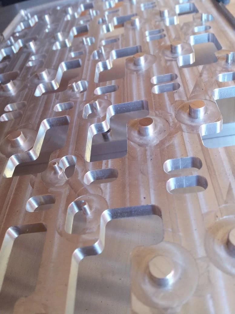 Base router aluminio CNC — detalle de cavidades y guías de posicionamiento